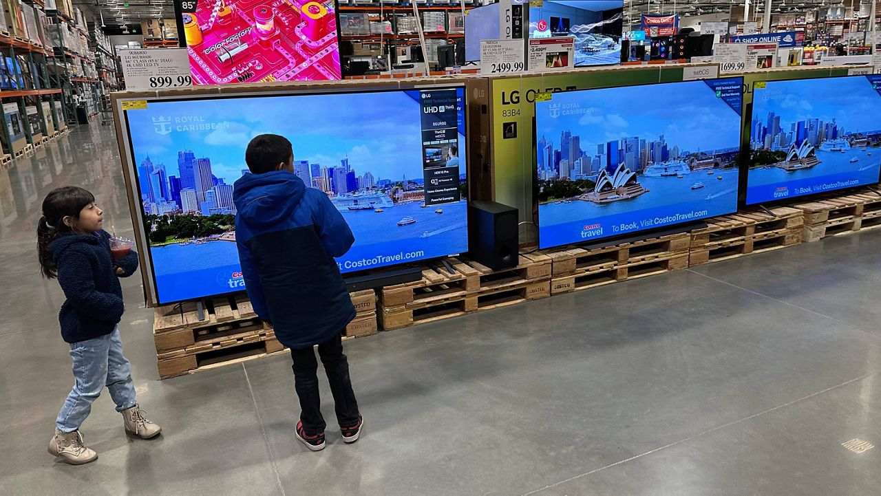 Young shoppers look over a row of large-screen televisions on display in a Costco warehouse Thursday, Dec. 19, 2024, in Denver. (AP Photo/David Zalubowski)