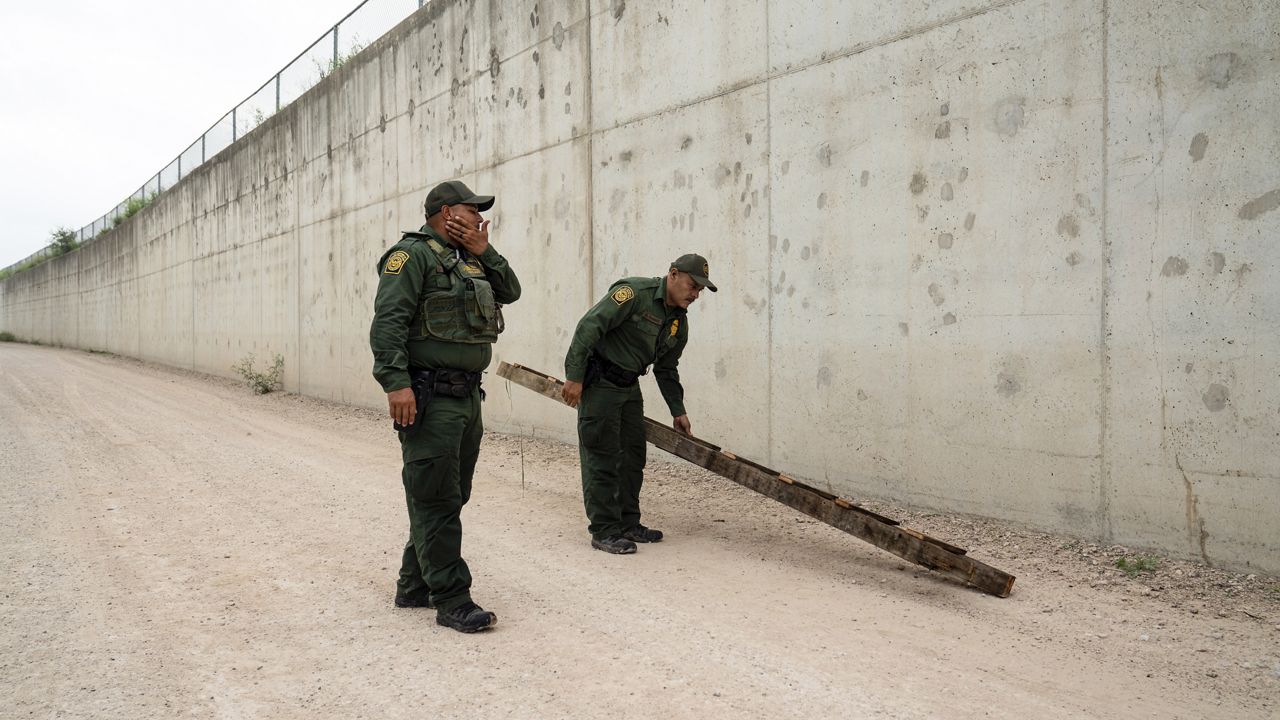 U.S. Border Patrol agents pick up a ladder that migrants carried to the border wall near the port of entry in Hidalgo, Texas, on May 4, 2023. (AP Photo/Veronica G. Cardenas)