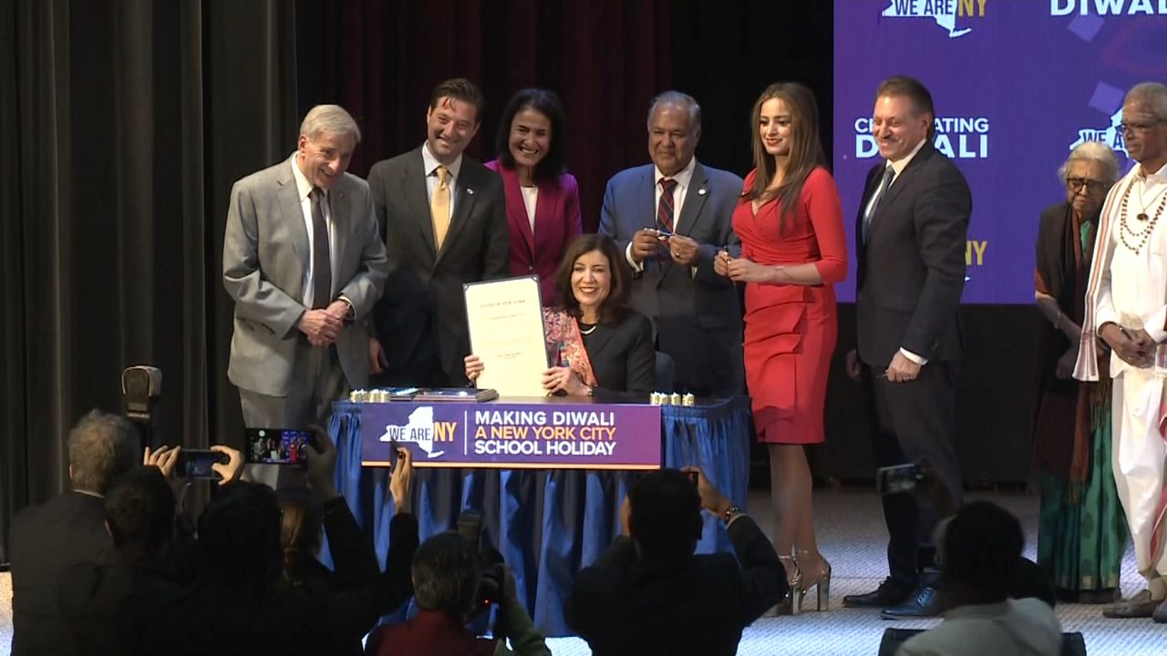 Gov. Kathy Hochul and other politicians are pictured signing a bill.