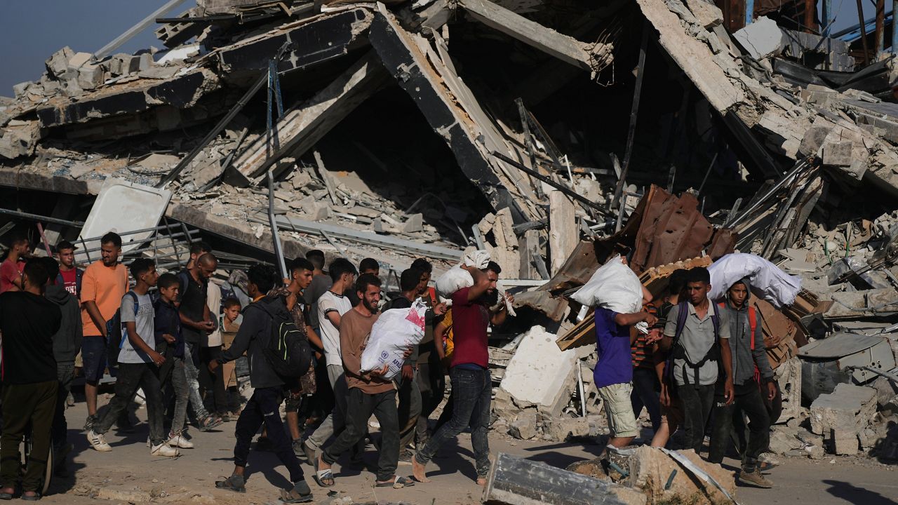 Palestinians carry humanitarian aid packages distributed by the Gaza Humanitarian Foundation operated by the U.S.-backed organization in Khan Younis, southern Gaza Strip, Thursday, June 26, 2025. (AP Photo/Abdel Kareem Hana)
