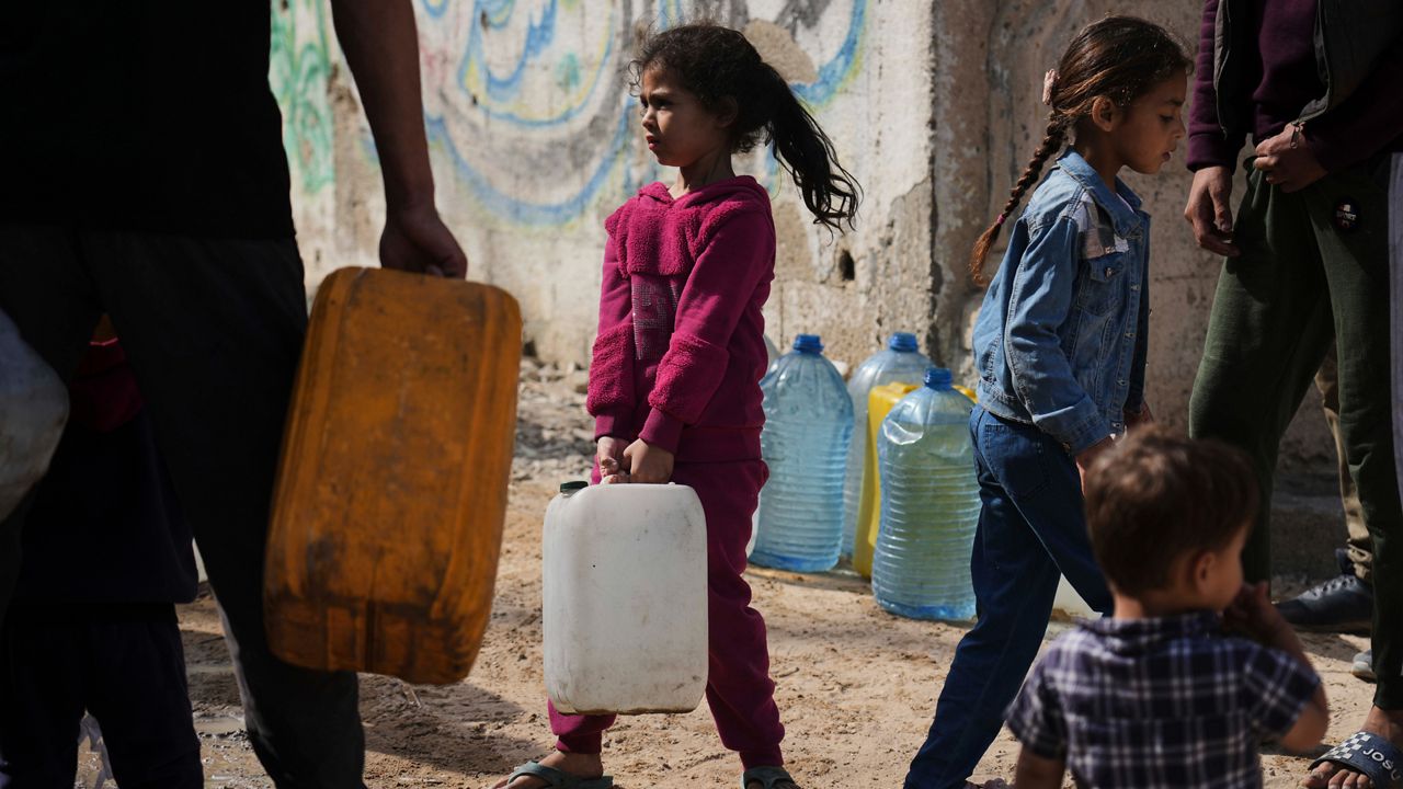 Palestinians collect water in jerrycans at a distribution point west of Gaza City, Sunday, May 11, 2025. (AP Photo/Jehad Alshrafi)