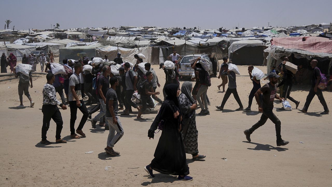 Palestinians carry bags containing food and humanitarian aid packages delivered by the Gaza Humanitarian Foundation, a U.S.-backed organization, in Rafah, southern Gaza Strip, Sunday, June 8, 2025. (AP Photo/Abdel Kareem Hana)