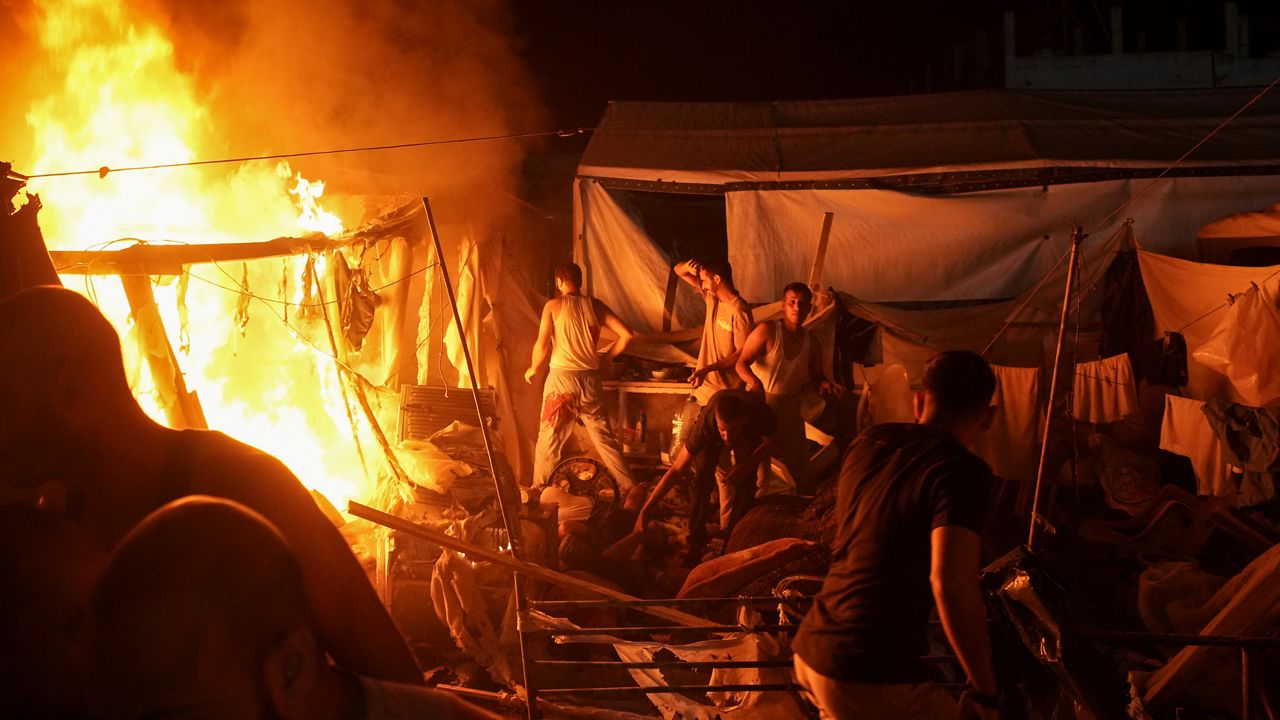 Palestinians react to fire from an Israeli strike that hit a tent area in the courtyard of Al Aqsa Martyrs hospital in Deir al Balah, Gaza Strip, Sunday, Aug. 4, 2024. The strike killed several people including a woman and injured others, health officials confirmed. (AP Photo/Abdel Kareem Hana)