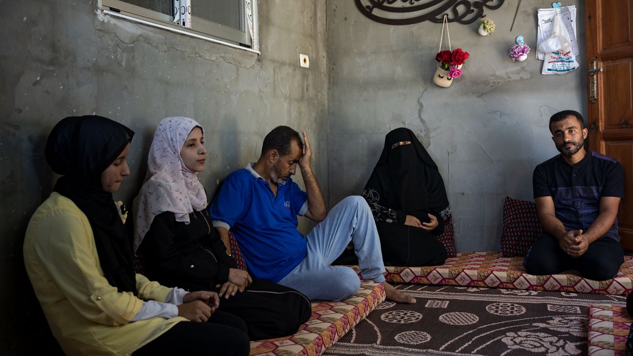 The Zorob family sits inside their one-room hut, covered in nylon sheets in Khan Younis, southern Gaza Strip, Monday, Aug. 28, 2023. The Gaza Strip's displaced families await the completion of nearly 1,400 Egyptian-sponsored housing units, a project mired in political disputes between the Palestinian Authority and Gaza's Hamas-run government. The Zorob family, like thousands of others, remains caught in the crossfire, living in makeshift conditions while nearly completed apartments stand empty.(AP Photo/Fatima Shbair)