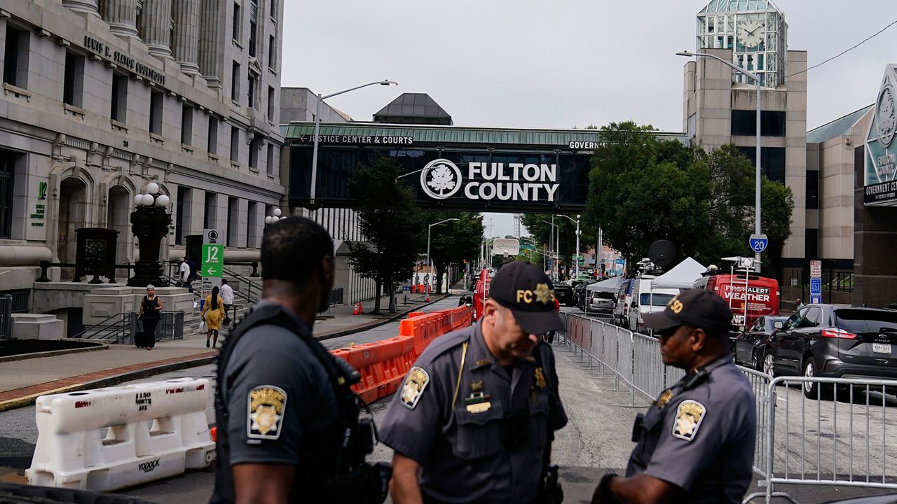 Authorities stand near barricades at the Fulton County courthouse, Monday, Aug. 7, 2023, in Atlanta. (AP Photo/Brynn Anderson)