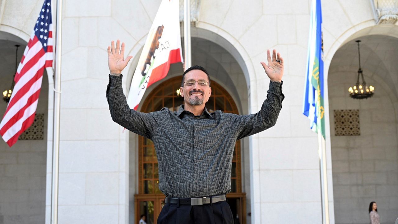 In this photo provided by The Innocence Center and the California Innocence Project, Gerardo Cabanillas waves from outside the Hall of Justice in downtown Los Angeles after his release on Tuesday, Sept. 26, 2023. (Laurence Colletti/Legal Talk Network via AP)