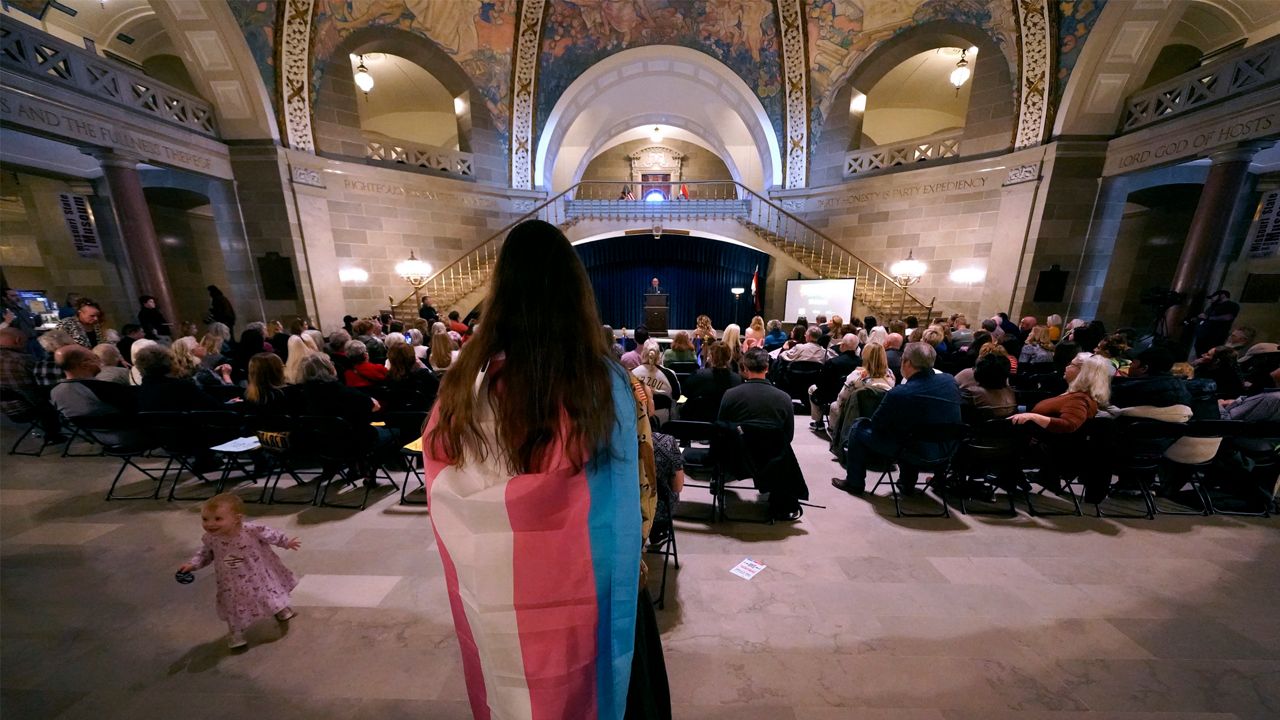 Glenda Starke wears a transgender flag as a counterprotest during a rally in favor of a ban on gender-affirming health care legislation, Monday, March 20, 2023, at the Missouri Statehouse in Jefferson City, Mo. (AP Photo/Charlie Riedel)