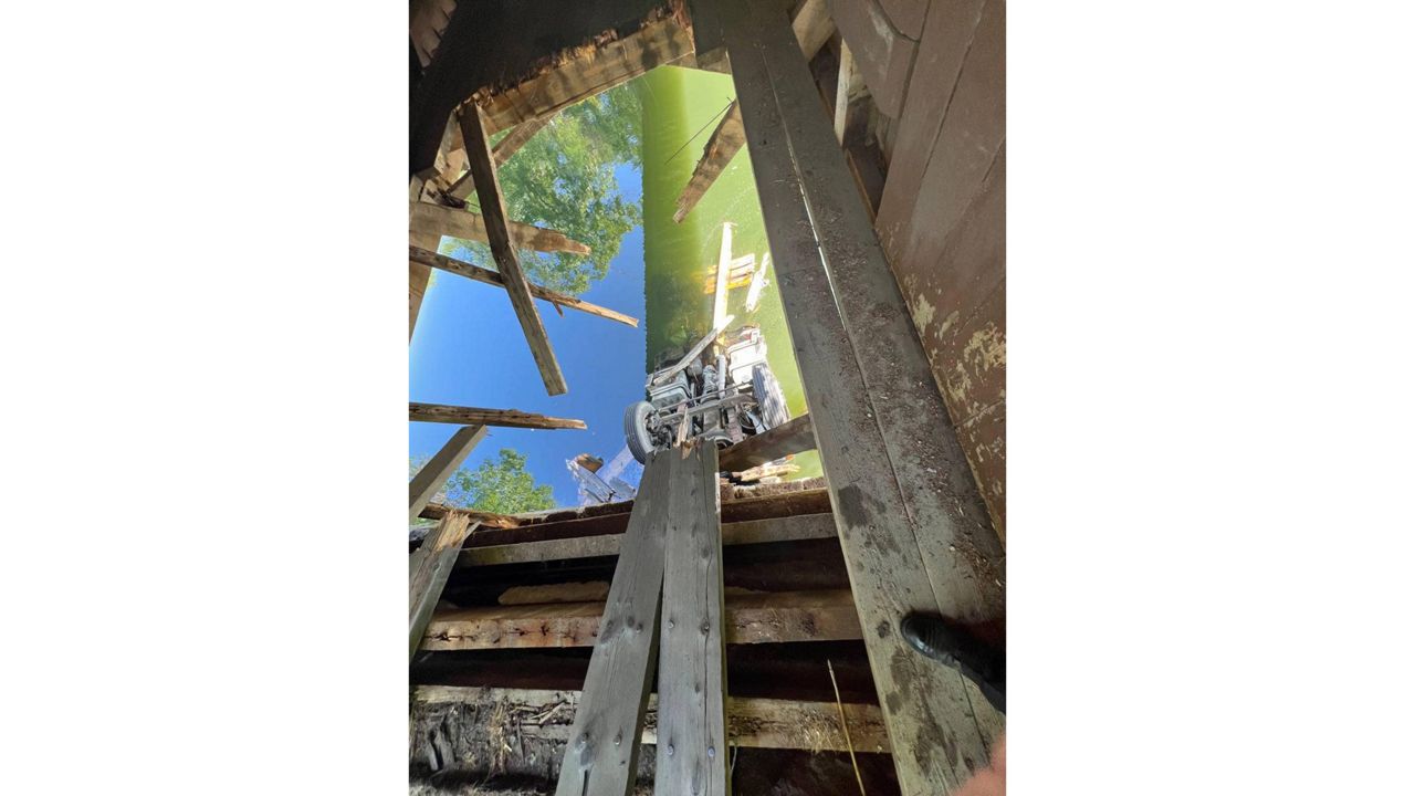 A view through the hole in the floor of Babbs Bridge in Gorham appears to show a large vehicle partly submerged in the Presumpscott River below. Police are warning the public that the bridge is now closed until further notice. (Gorham Police Department)