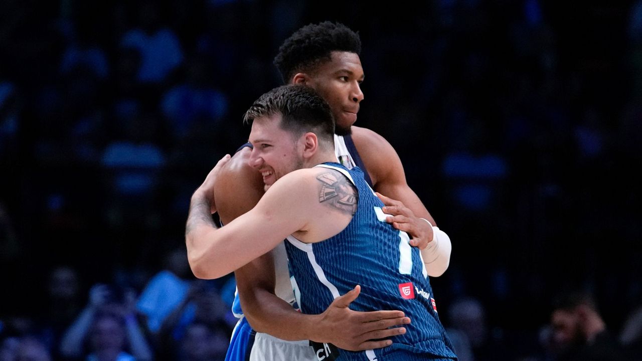 Greece's Giannis Antetokounmpo, rear, hugs Slovenia's Luka Doncic ahead of a basketball match, during the Acropolis basketball tournament at the Peace and Friendship indoor stadium at Athens' port city of Piraeus, Saturday, July 6, 2024. (AP Photo/Petros Giannak ouris)