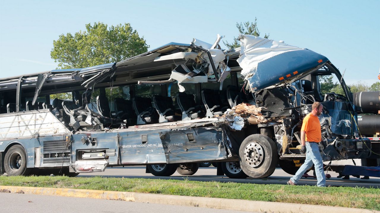 A worker helps clear the wreckage of a Greyhound bus that collided with tractor-trailers on the exit ramp to a rest area on westbound Interstate 70 in Highland, Ill., on Wednesday, July 12, 2023. (Christian Gooden/St. Louis Post-Dispatch via AP)