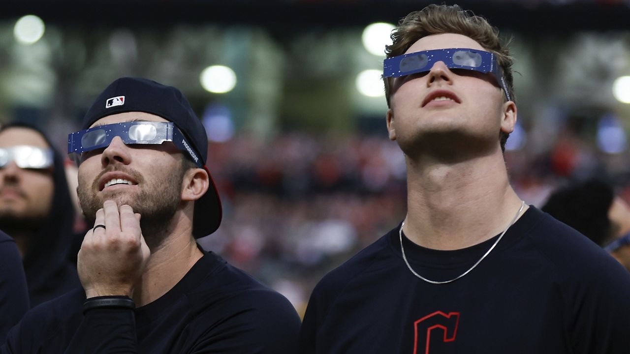 Cleveland Guardians first base David Fry (6) and Tim Herrin uses special glasses to watch the total solar eclipse, Monday, April 8, 2024, in Cleveland. (AP Photo/Ron Schwane)
