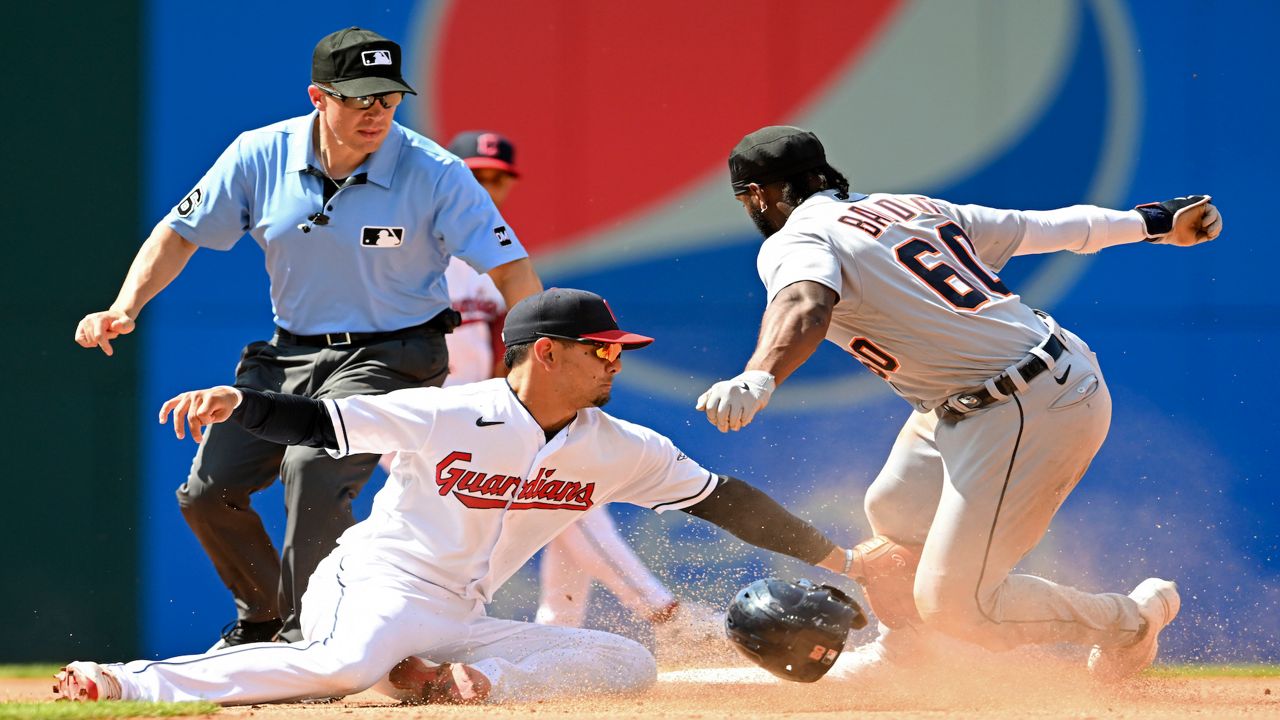 baseball players at home plate, with one losing his head gear