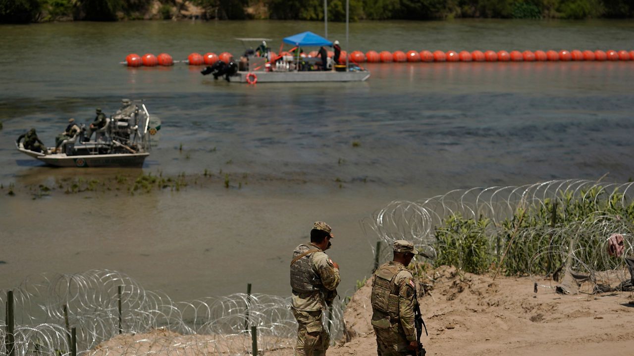 Guardsmen patrol as workers continue to deploy large buoys to be used as a border barrier along the banks of the Rio Grande in Eagle Pass, Texas, Wednesday, July 12, 2023. The floating barrier is being deployed in an effort to block migrants from entering Texas from Mexico. (AP Photo/Eric Gay)