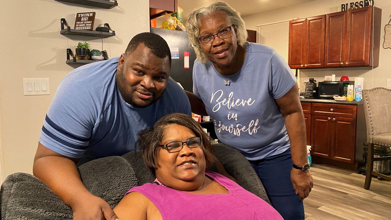 Vickey Cambell (center), her son, Danny (left) and mother, Joan (right) pose for a family photo in their Habitat for Humanity home in Apopka. (Spectrum News/Molly Duerig)