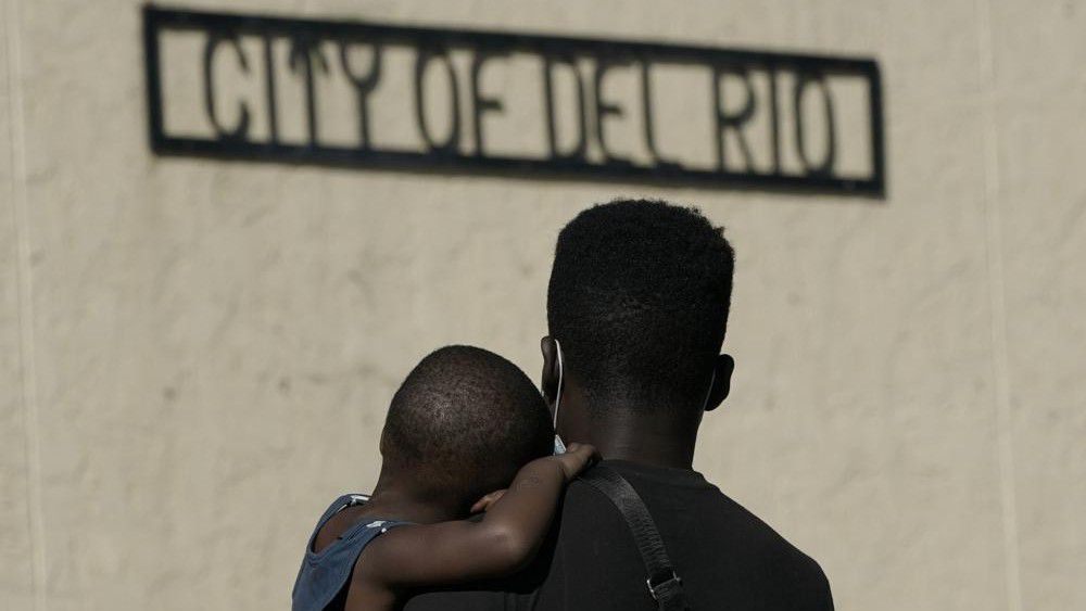 A Haitian migrant carries a boy while waiting to board a bus provided by a humanitarian group after being released from U.S. Customs and Border Protection custody, Friday, Sept. 24, 2021, in Del Rio, Texas. The “amistad,” or friendship, that Del Rio, Texas, and Ciudad Acuña, Mexico, celebrate with a festival each year has been important in helping them deal with the challenges from a migrant camp that shut down the border bridge between the two communities for more than a week. Federal officials announced the border crossing would reopen to passenger traffic late Saturday afternoon and to cargo traffic on Monday. (AP Photo/Julio Cortez)