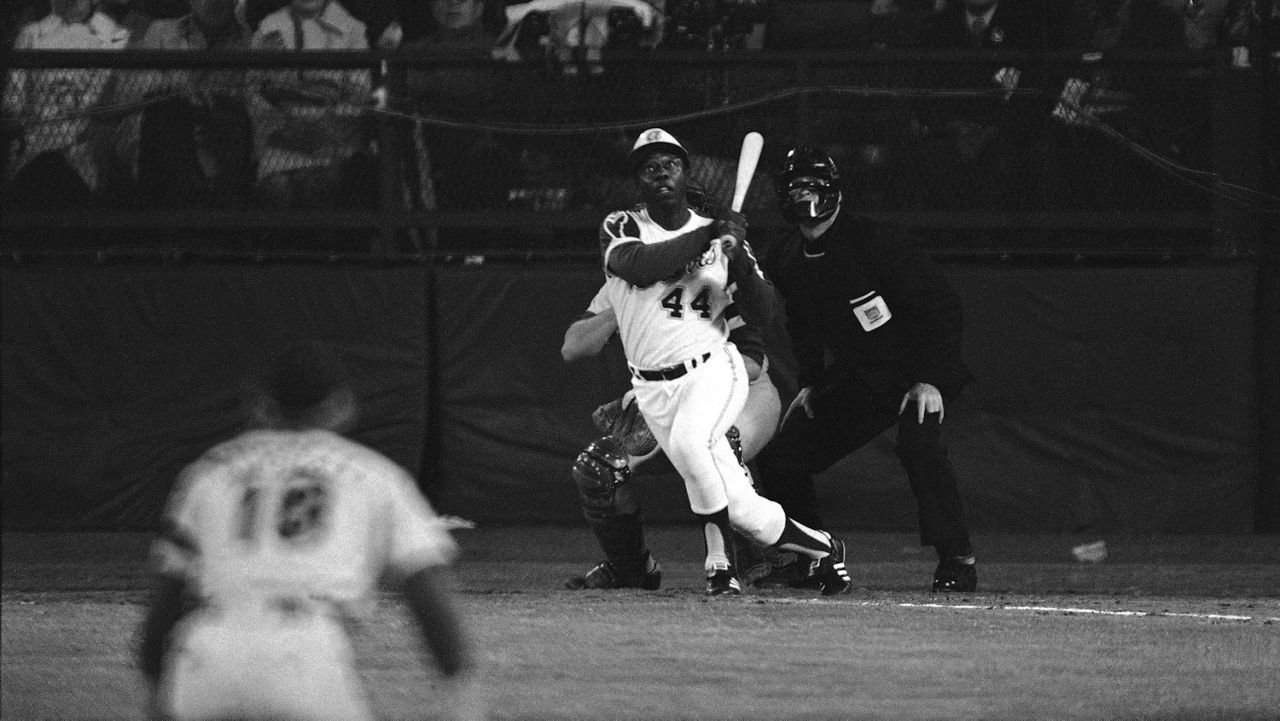 Atlanta Braves' Hank Aaron eyes the flight of the ball after hitting his 715th career homer in a game against the Los Angeles Dodgers in Atlanta, Ga., Monday night, April 8, 1974. Aaron broke Babe Ruth's record of 714 career home runs. Dodgers southpaw pitcher Al Downing, catcher Joe Ferguson and umpire David Davidson look on. (AP Photo/Harry Harris, File)