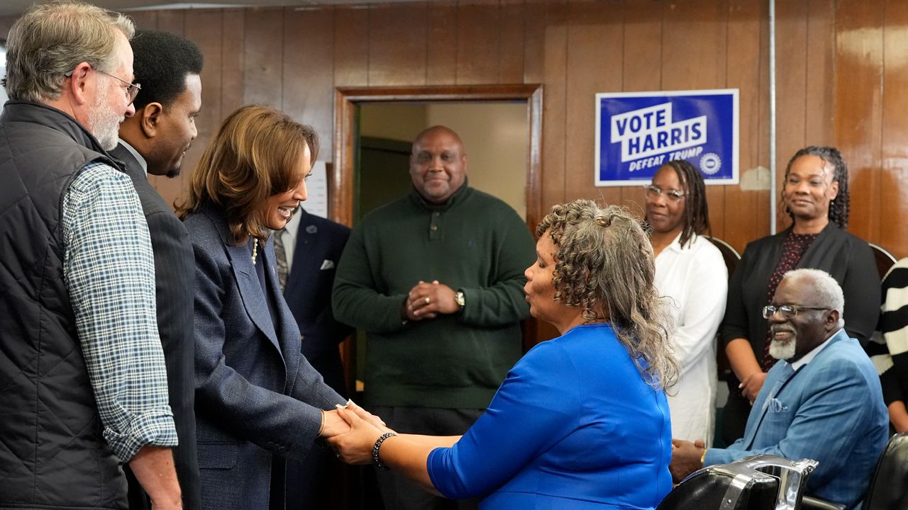 Democratic presidential nominee Vice President Kamala Harris, third left, greets Martha Roland, seated center right, and Roland Elam Sr., seated right, parents of Elam's barber shop owner Roland Elam Jr., second left, as Sen. Gary Peters, D-Mich., left, and others look on before participating in a roundtable discussion with local leaders at Elam's barber shop in Pontiac, Mich., Sunday, Nov. 3, 2024. (AP Photo/Jacquelyn Martin)