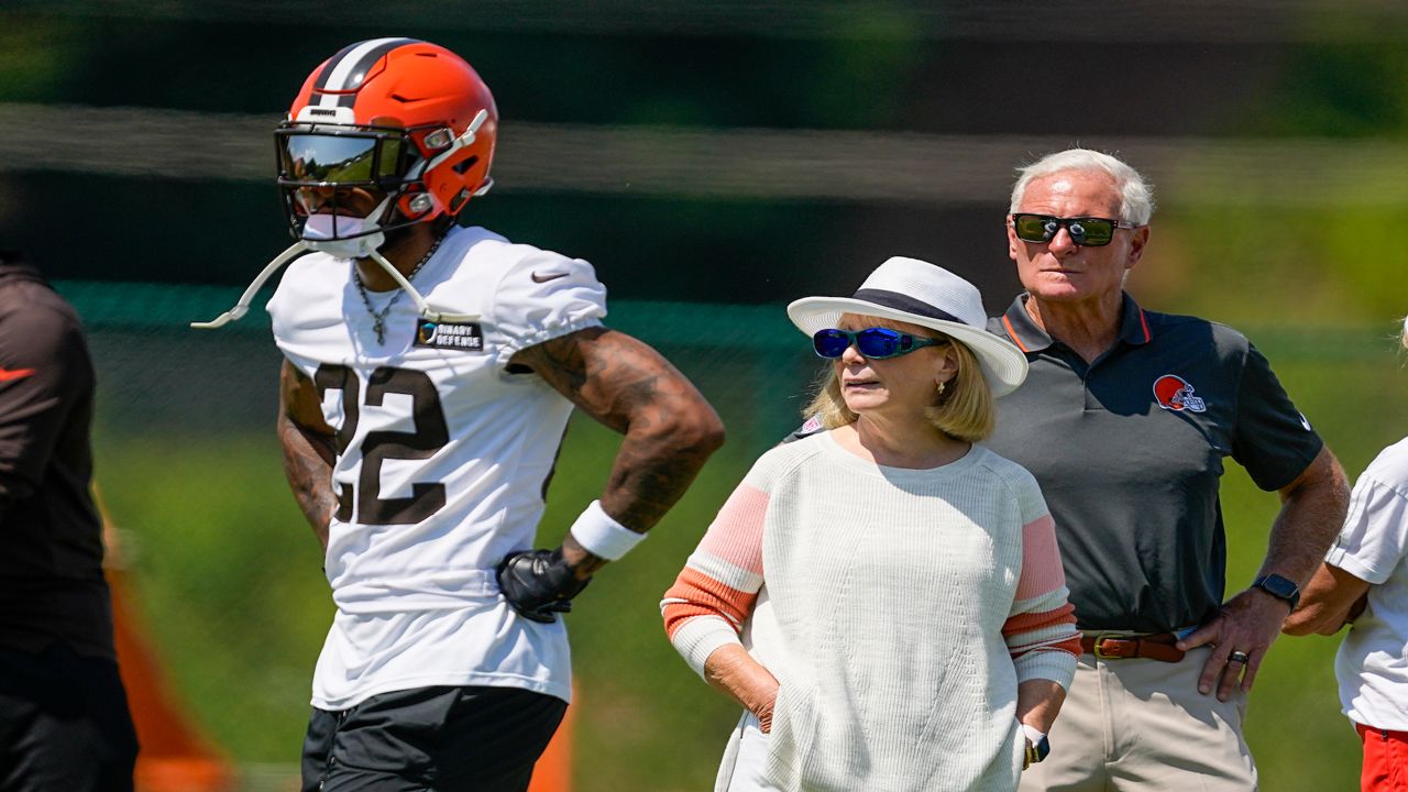 two people watch football near one player in a Cleveland Browns jersey