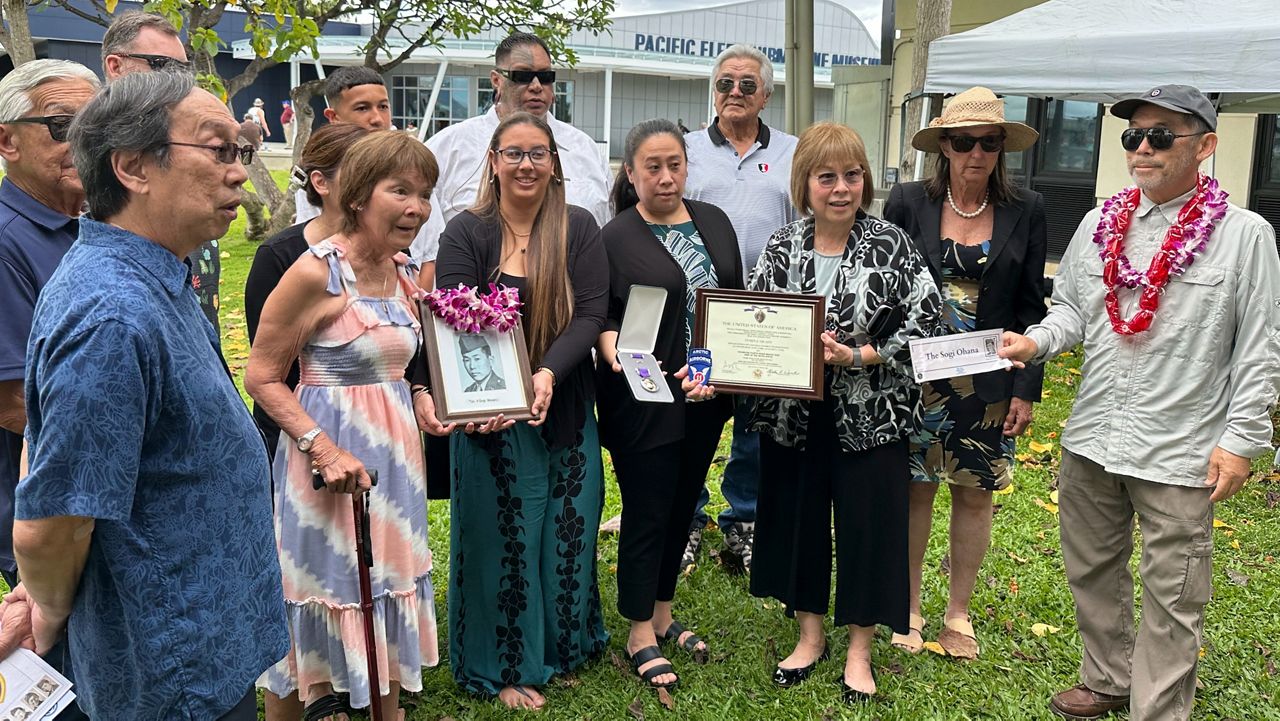 Members of the Sogi family hold a photo of Masaru Sogi and the Purple Heart medal posthumously awarded to him, in Pearl Harbor, Hawaii, on Friday, May 10, 2024. (AP Photo/Audrey McAvoy)