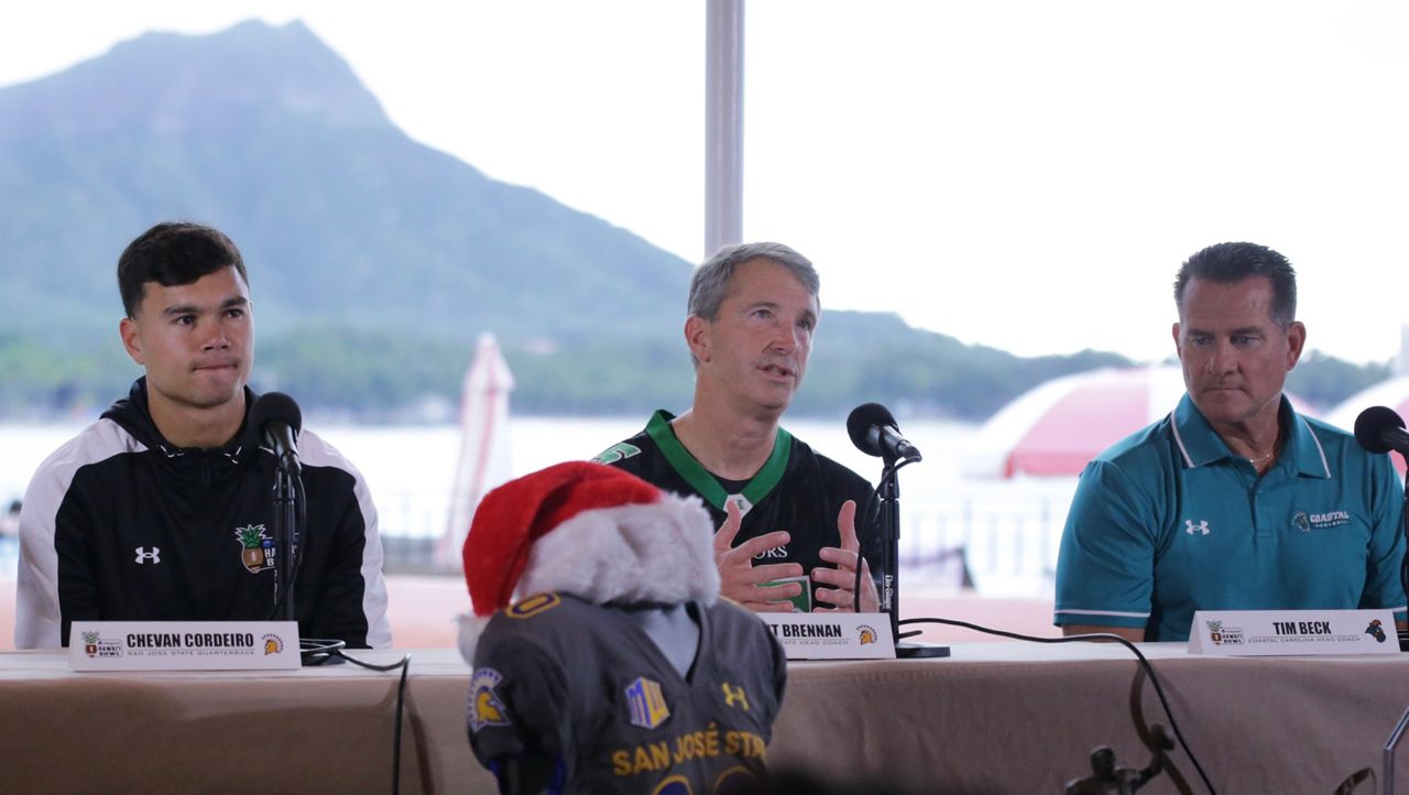 San Jose State head coach Brent Brennan, middle, spoke at the EasyPost Hawaii Bowl introductory press conference at the Royal Hawaiian Hotel on Tuesday morning. At left was Spartans quarterback Chevan Cordeiro, a Saint Louis School graduate and ex-Hawaii player, and Coastal Carolina coach Tim Beck, right. Brennan wore a throwback jersey of his cousin Colt Brennan, the late former UH quarterback.