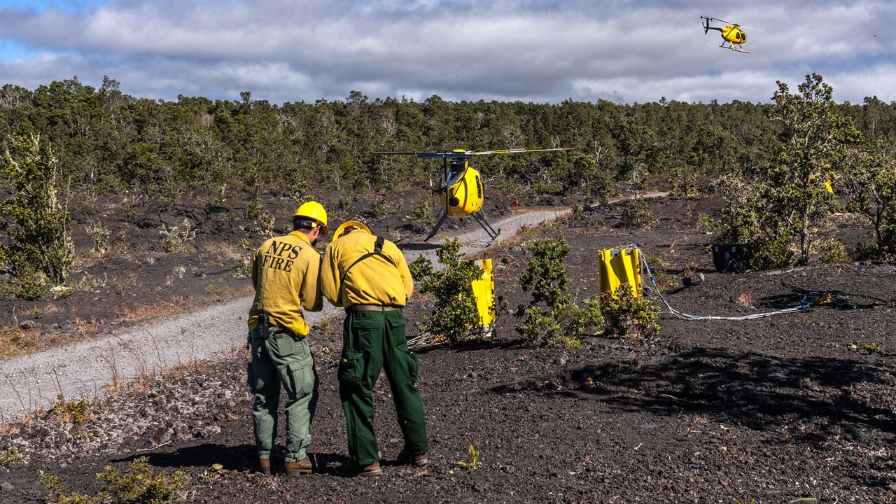 Two NPS firefighters and helicopters assigned to the Makaopuhi Fire. (Photo courtesy of National Park Service/J. Wei)