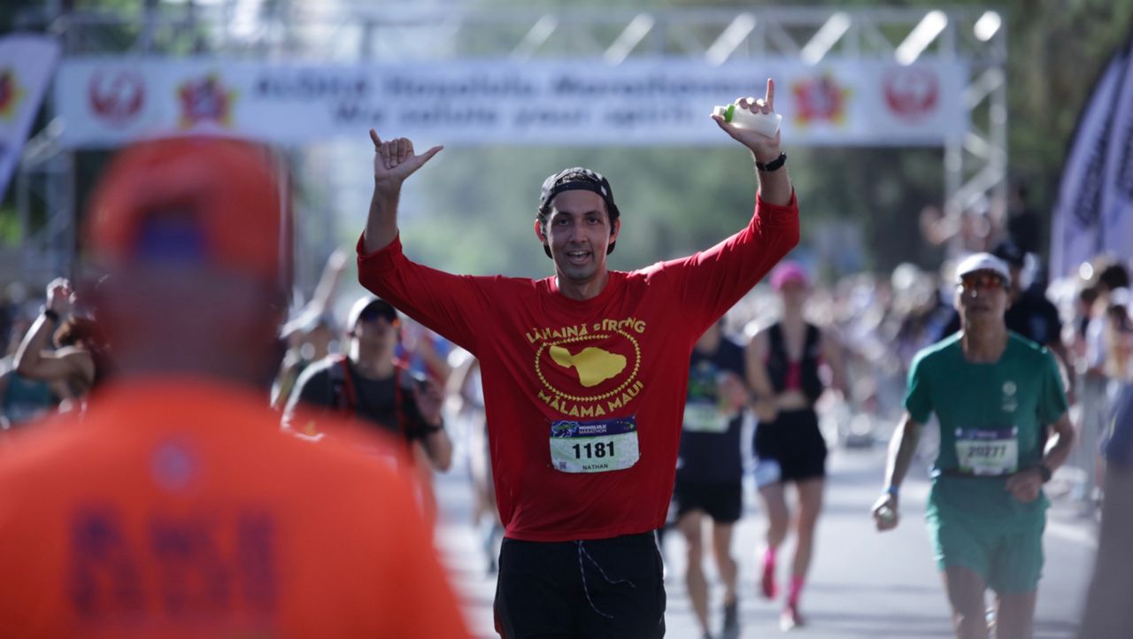 Lahaina Intermediate health teacher Nathan Kahaiali‘i, wearing one of his "Lahaina Strong" fundraiser shirts, flashed shakas as he prepared to cross the finish line at the 2023 Honolulu Marathon.