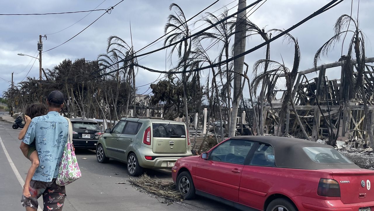 Lance and his baby boy, who narrowly escaped the fire, walking through Lahaina. (Photo courtesy of Dustin Tester)