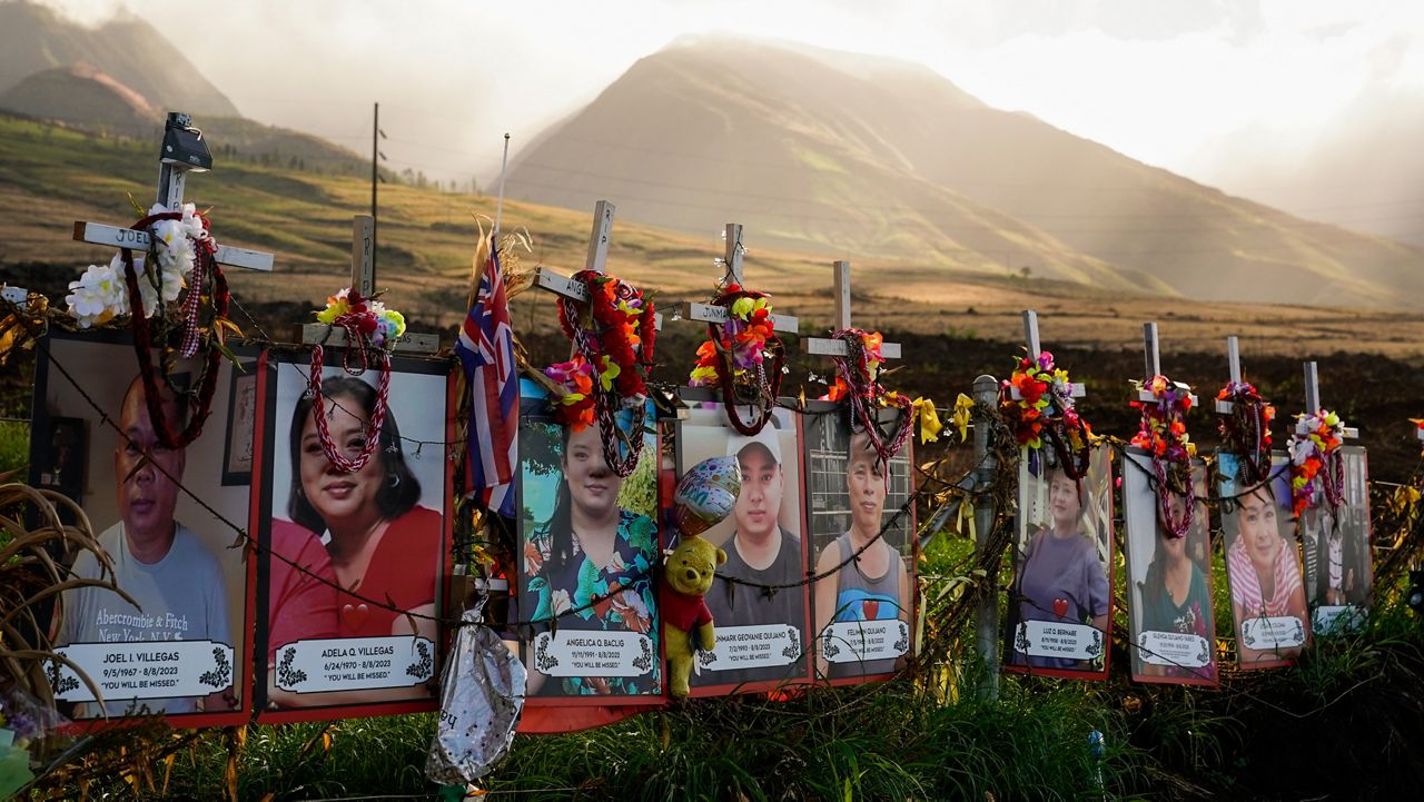 Photos of victims are displayed under white crosses at a memorial for the August 2023 wildfire victims, above the Lahaina Bypass highway, Dec. 6, 2023, in Lahaina, Hawaii. The Maui Fire Department is expected to release a report Tuesday, April 16, 2024, detailing how the agency responded to a series of wildfires that burned on the island during a windstorm last August. (AP Photo/Lindsey Wasson, File)