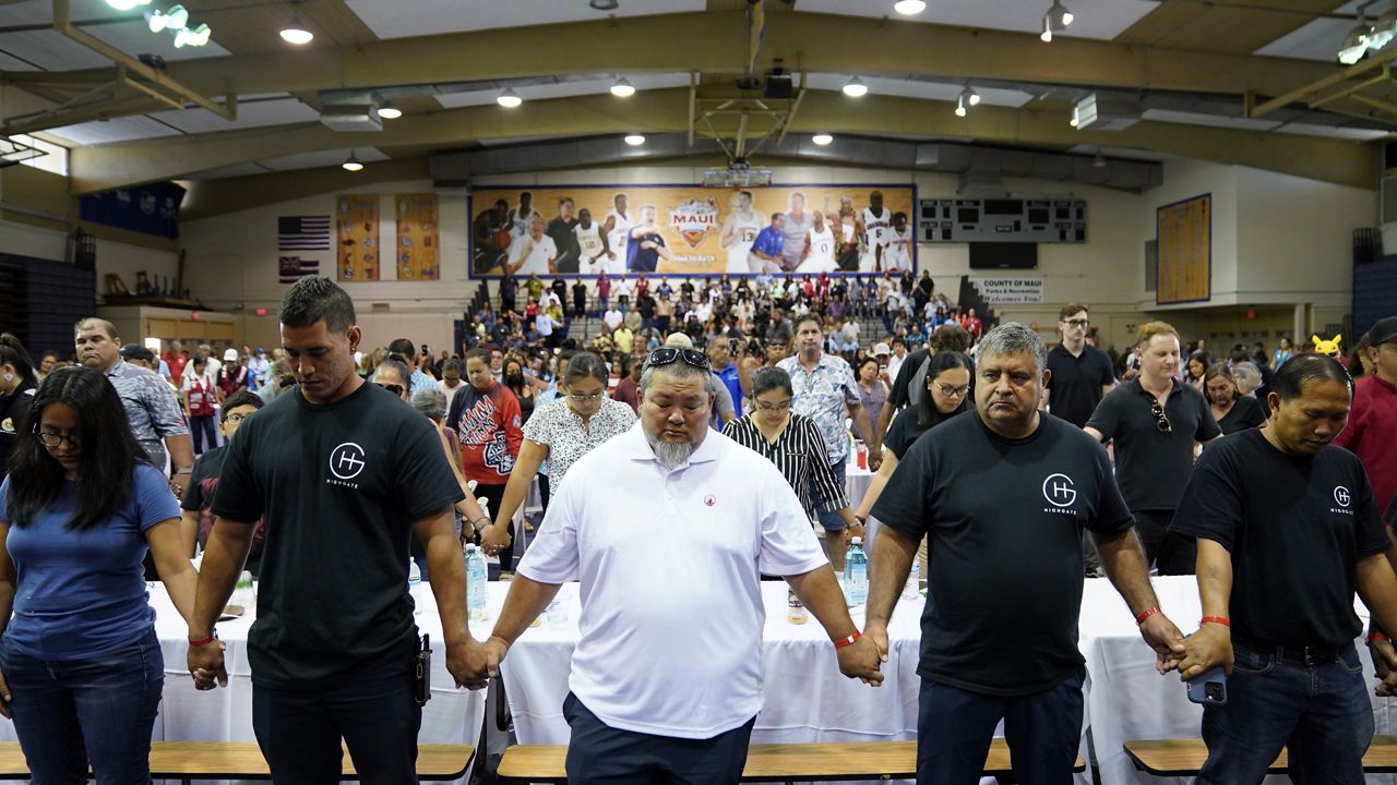 People prayed as President Joe Biden and first lady Jill Biden met with West Maui community members impacted by the Aug. 8 wildfires at Lahaina Civic Center on Aug. 21. The Maui Invitational basketball mural is visible in the background. The event's operator, KemperSports, announced Thursday that the prestigious early-season college basketball tournament will return to the LCC in November after being moved to Oahu in 2023 due to the nearby devastation.