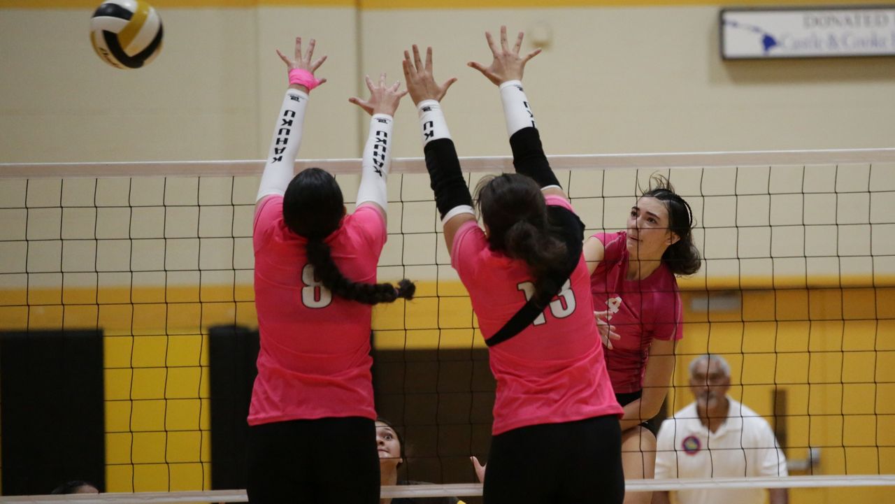 Mililani hitter Erica Roberts elevated for a swing against Kahuku's Sidney Keni (8) and Maia Esera (13) on Thursday night. 