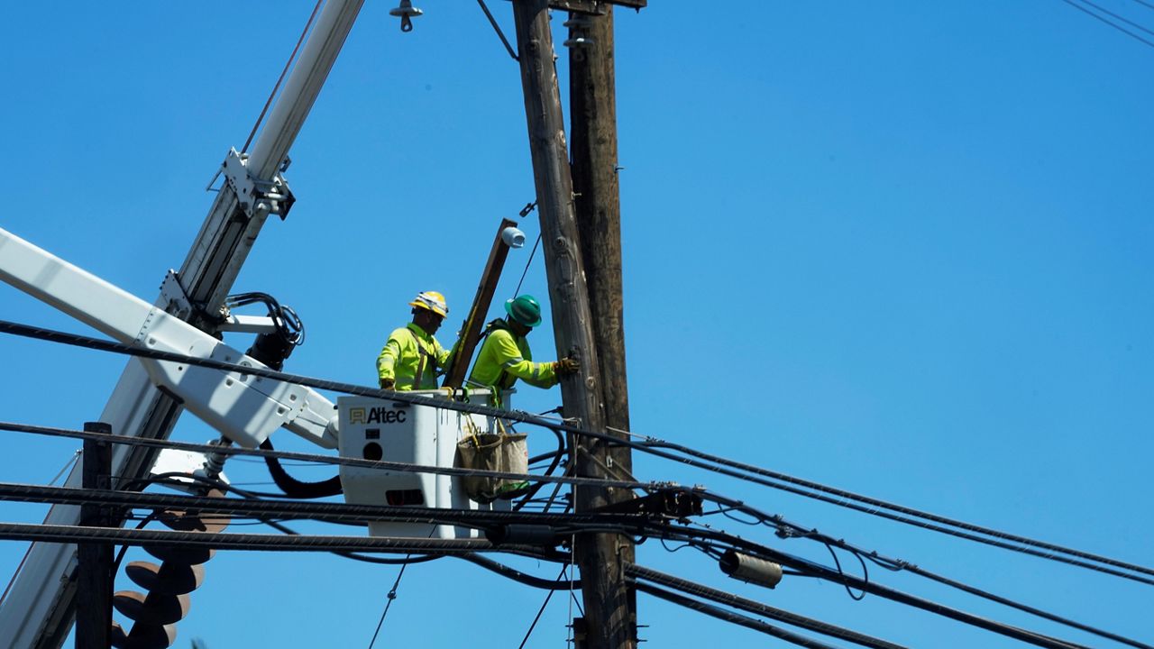 Linemen work on poles, Sunday, Aug. 13, 2023, in Lahaina, Hawaii, following a deadly wildfire that caused heavy damage days earlier. (AP Photo/Rick Bowmer)