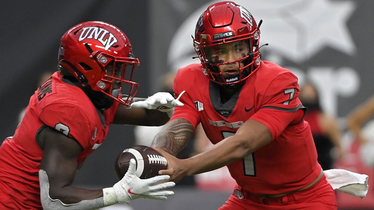 UNLV quarterback Cameron Friel, a Kailua High graduate, handed off the ball to running back Charles Williams against Hawaii on Nov. 13, 2021, in Las Vegas.