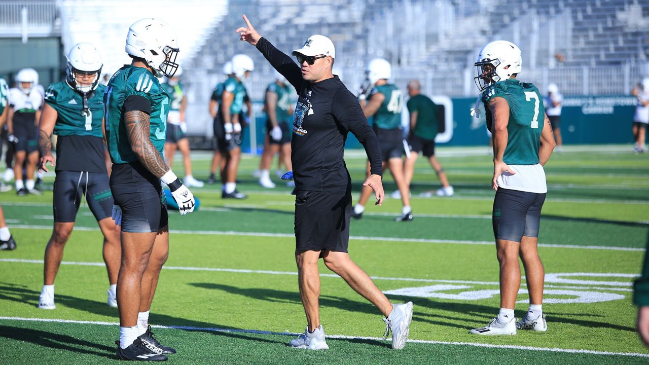 Hawaii football coach Timmy Chang, middle, gave instructions to the UH defense during a drill on Day 1 of fall practices on Wednesday.