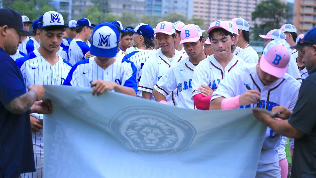 Players from Maui High (left) and Baldwin (right) signed an HHSAA championship banner after they were declared the Division I baseball co-champions at Moanalua High on Saturday.