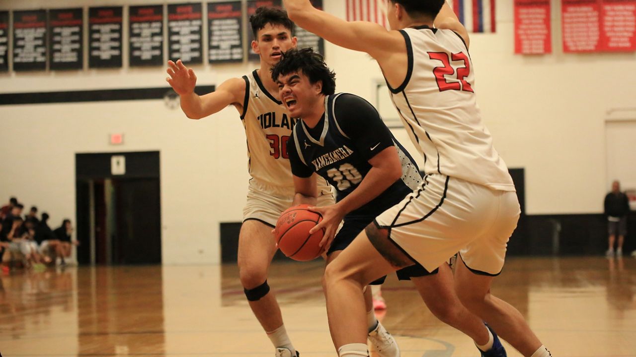 Kamehameha guard Christian Togiai split Iolani's Mana Lau Kong (30) and Luke Tobin (22) on his way to the basket in the second half of an ILH playoff game at the Raiders' gym.