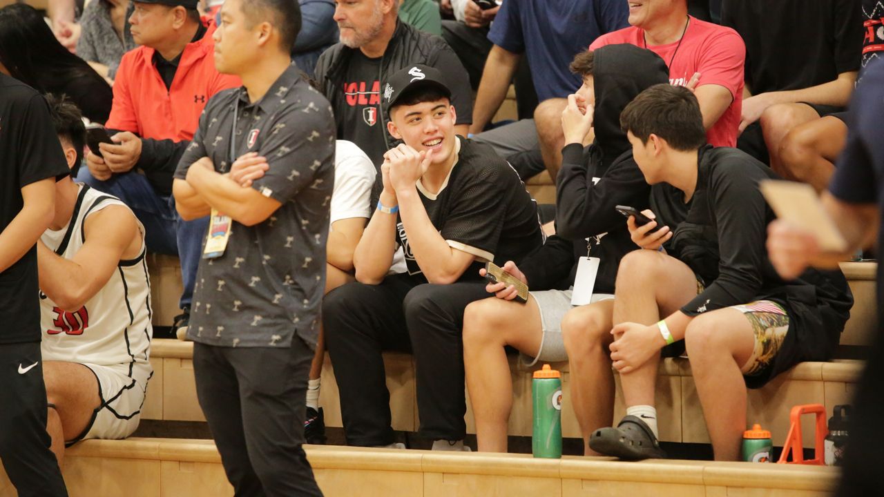 Former Iolani guard JJ Mandaquit, middle, sat behind the Raiders' bench during warmups for the Iolani Prep Classic quarterfinals in December.