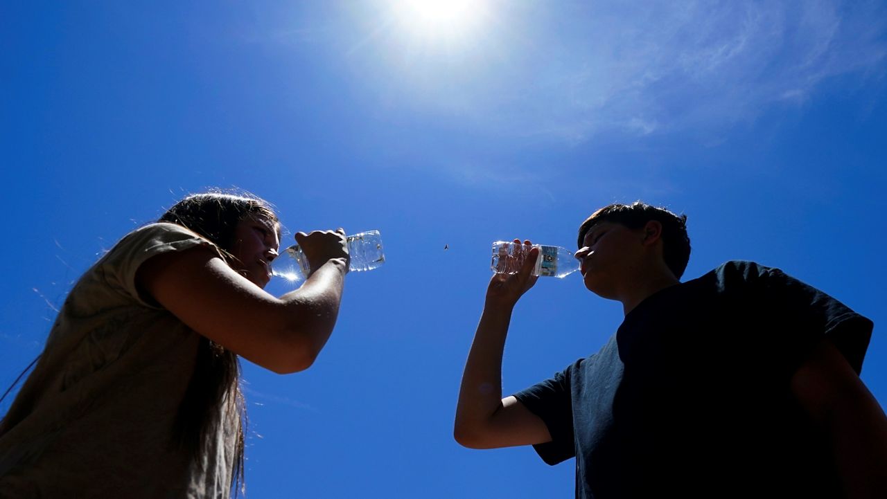 FILE - Tony Berastegui Jr., 15, right, and his sister Giselle Berastegui, 12, drink water July 17, 2023, in Phoenix. (AP Photo/Ross D. Franklin, File)