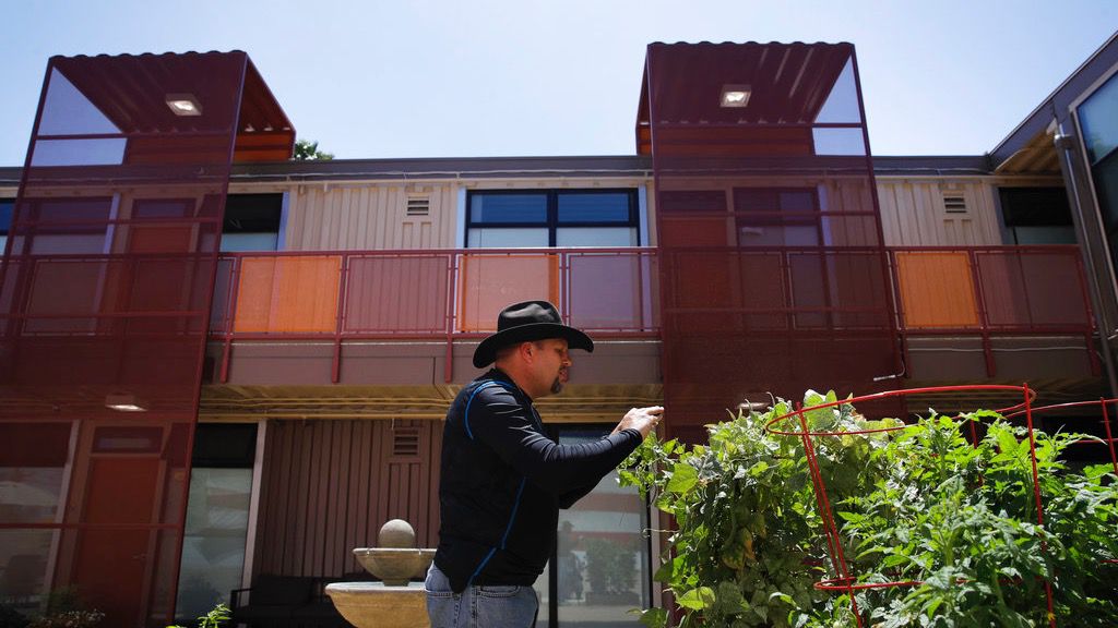 A once-homeless Iraq war veteran takes pictures of plants in the courtyard of his apartment complex, reserved just for homeless veterans. (AP Photo/Jae C. Hong)