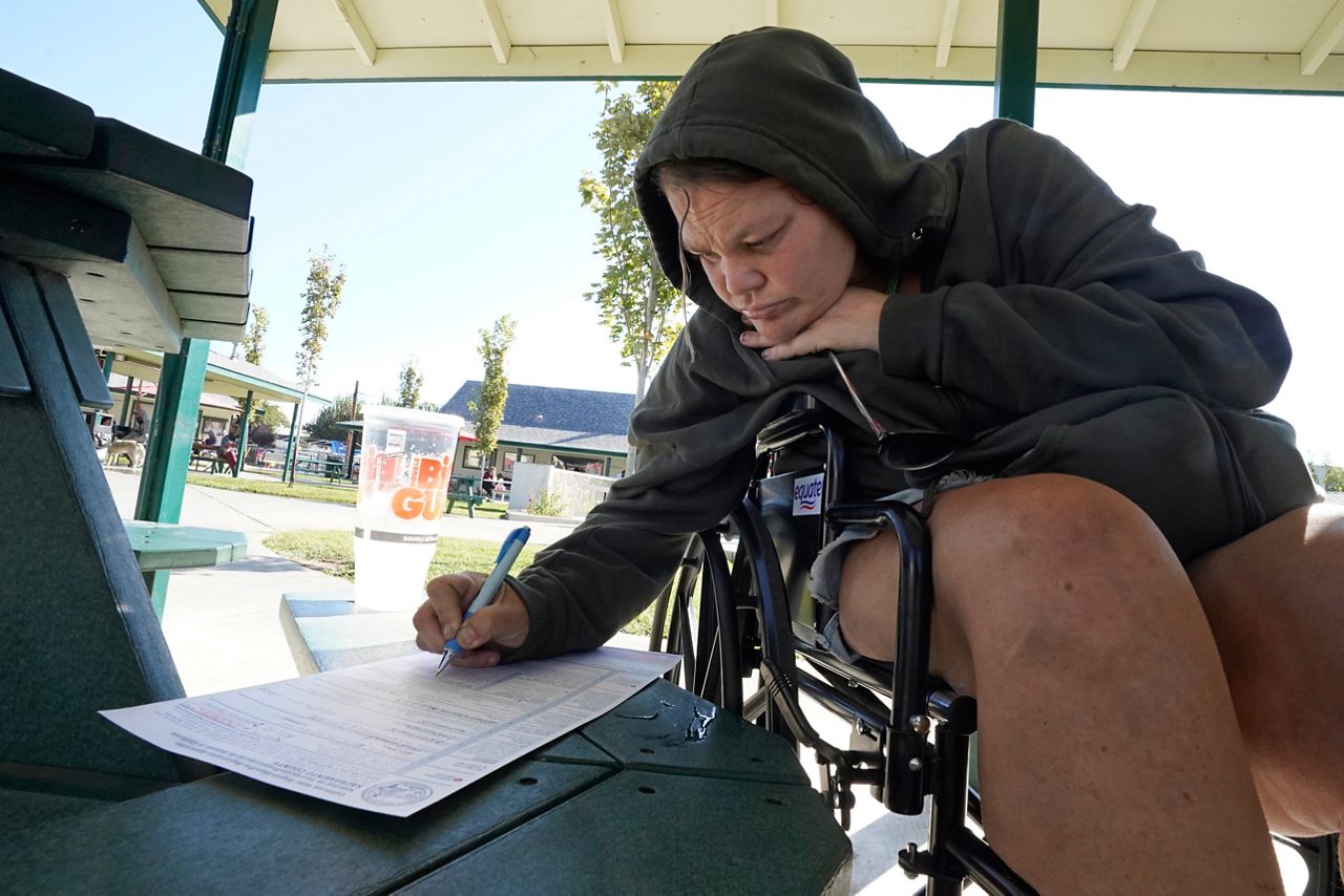 Elisha McDonald, who's been without a home since February, signs voter registration in Sacramento, Calif., on Thursday, Oct. 13, 2022. AP Photo/Rich Pedroncelli)