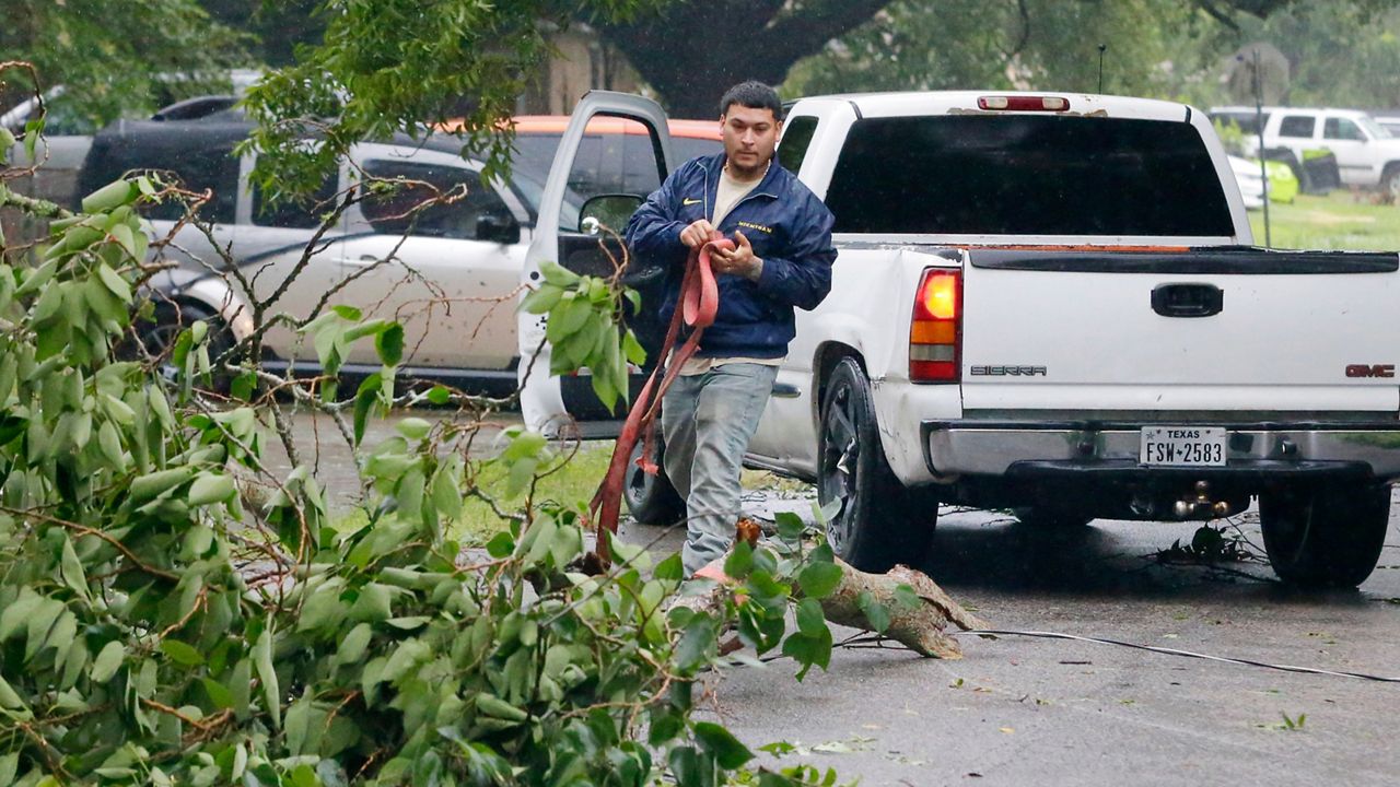 William Ruiz uses a tow strap and his pick-up truck to remove a downed tree branch from the middle of the street in his neighborhood during a lull as the eye of Hurricane Beryl passes through Monday, July 8, 2024, in Rosenberg, Texas. (AP Photo/Michael Wyke)