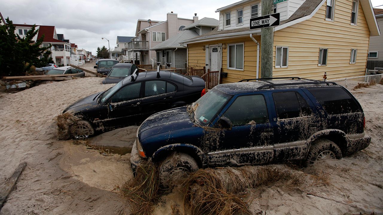 In this Oct. 30, 2012 photo, cars lifted by floodwater are mired in several feet of sand in the aftermath of Superstorm Sandy, in Long Beach, N.Y. (AP Photo/Jason DeCrow)