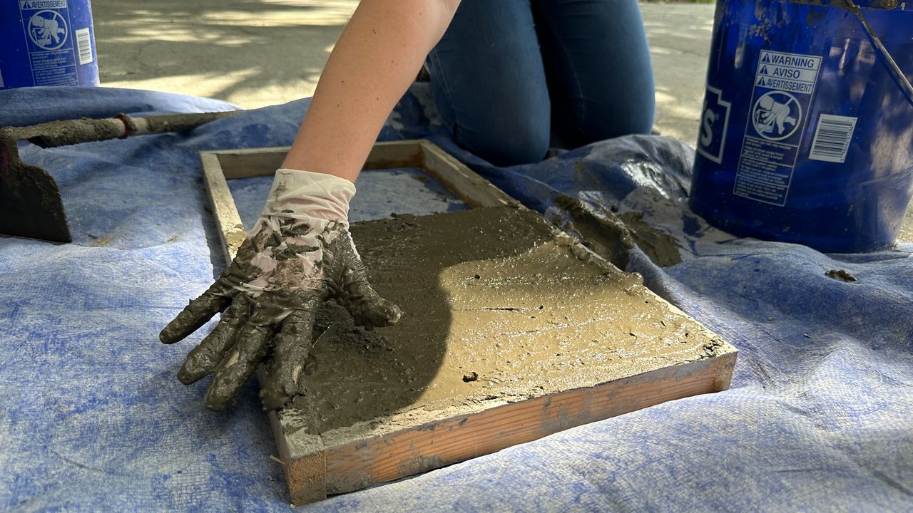 Sophia Weiner, 18, adds muck-rete to a paver mold. She came up with idea for muck-rete in sixth grade when she discovered that muck from the Indian River Lagoon can be used as an aggregate in concrete. (Spectrum News)