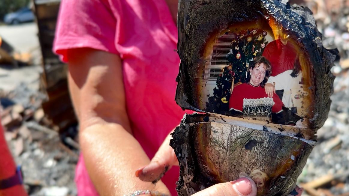 Debbie Sherwood found what was left of a photo album in the ashes of her home. (Spectrum News 1/Rachel Boyd)