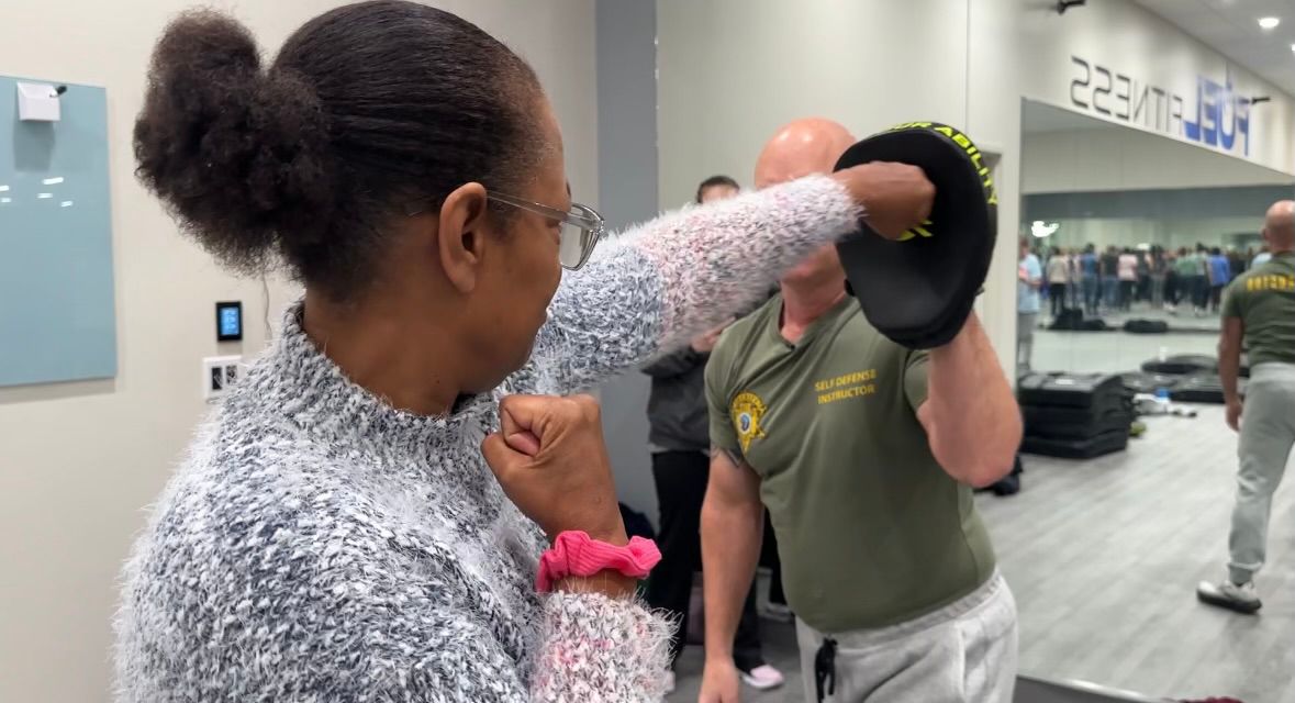 A woman practicing striking with Corporal Tim Shortt.