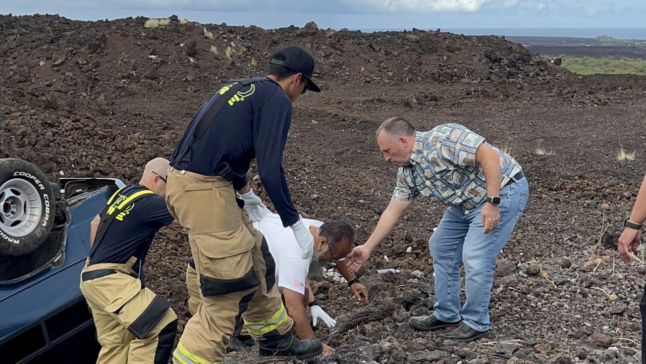 Gov. Josh Green reaches down to help a wounded driver on Thursday on Hawaii Island after a man's vehicle flipped upside down in a lava field. (Photo courtesy the Office of the Governor)