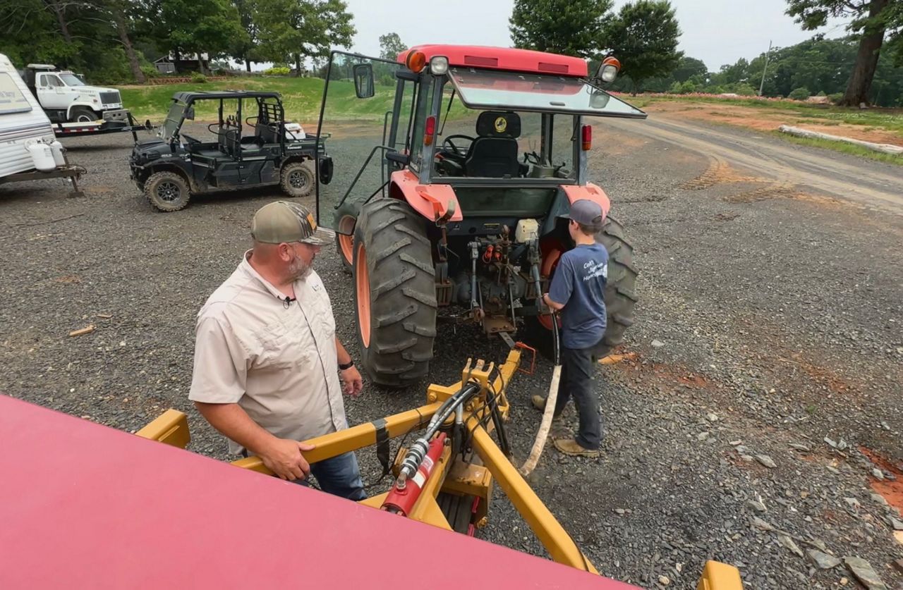 Chris and Colt Crump work on machinery at their farm in Belews Creek. (Spectrum News 1/Sydney McCoy)