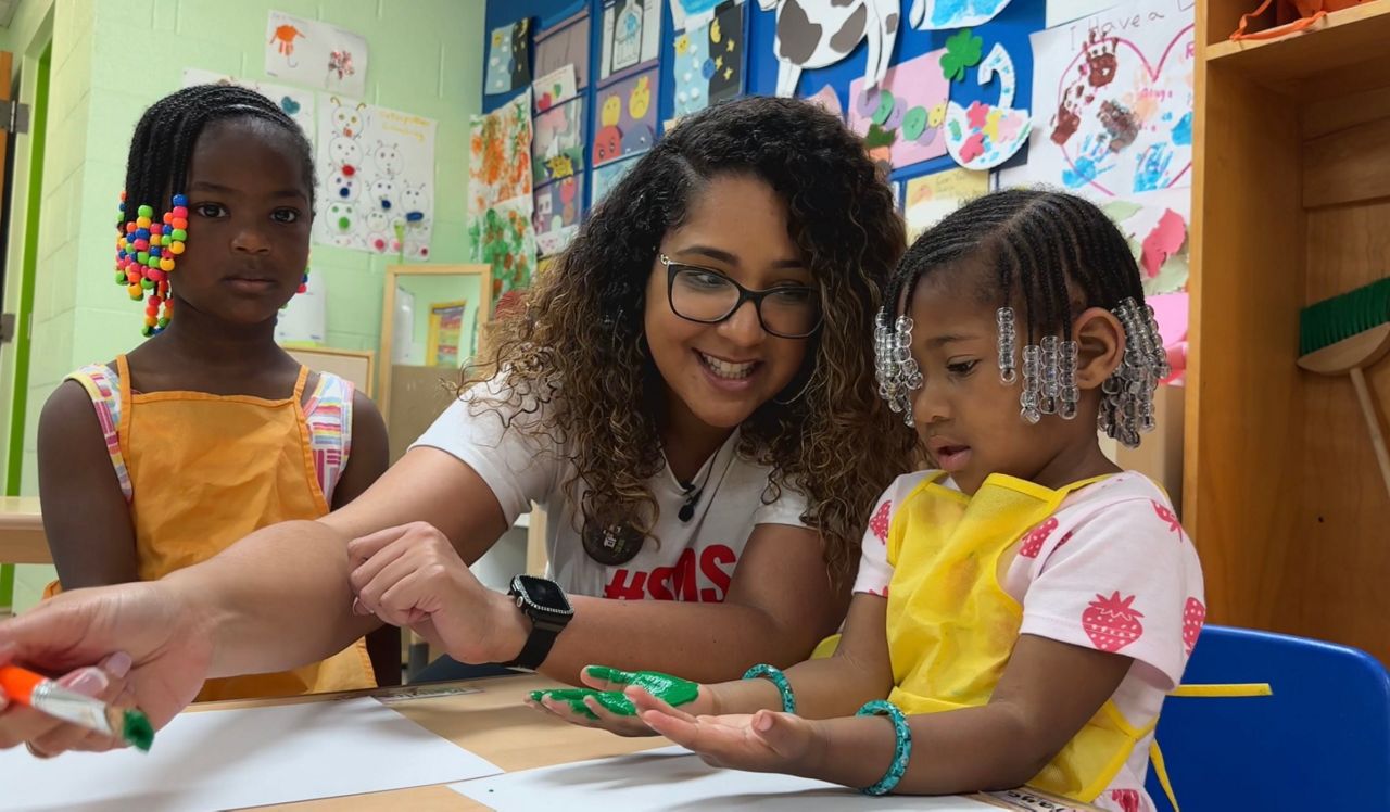 Betsy Rodriguez painting kids hands to make into dinosaurs.