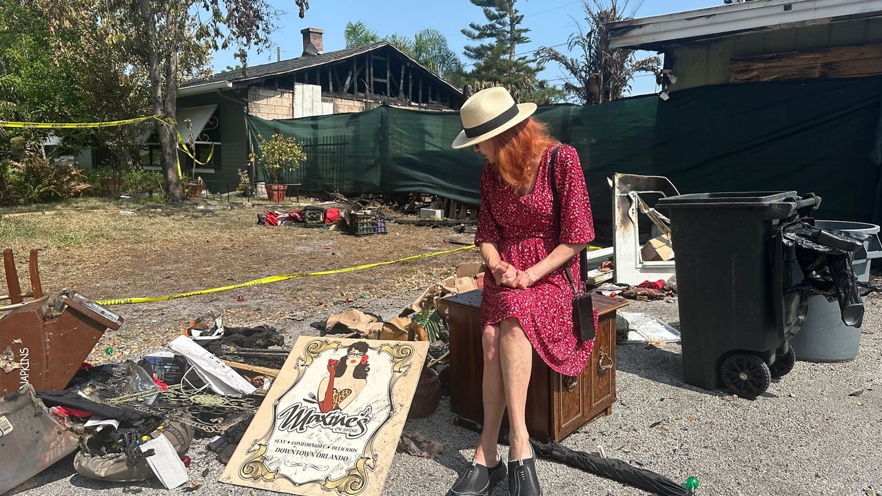 As Maxine Earhart looks around her front yard, it’s a scene that’s still hard to process, as she goes through some of her belongings laying on the ground burnt following a Sunday morning fire at her home. (Spectrum News/Massiel Leyva)