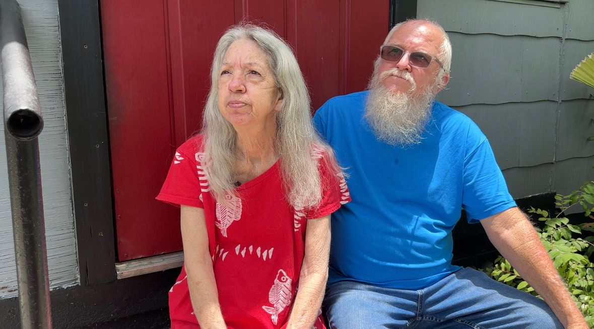 George and Diane Flood sitting outside of their house, talking about the Disaster Readiness and Recovery Program. (Spectrum News)