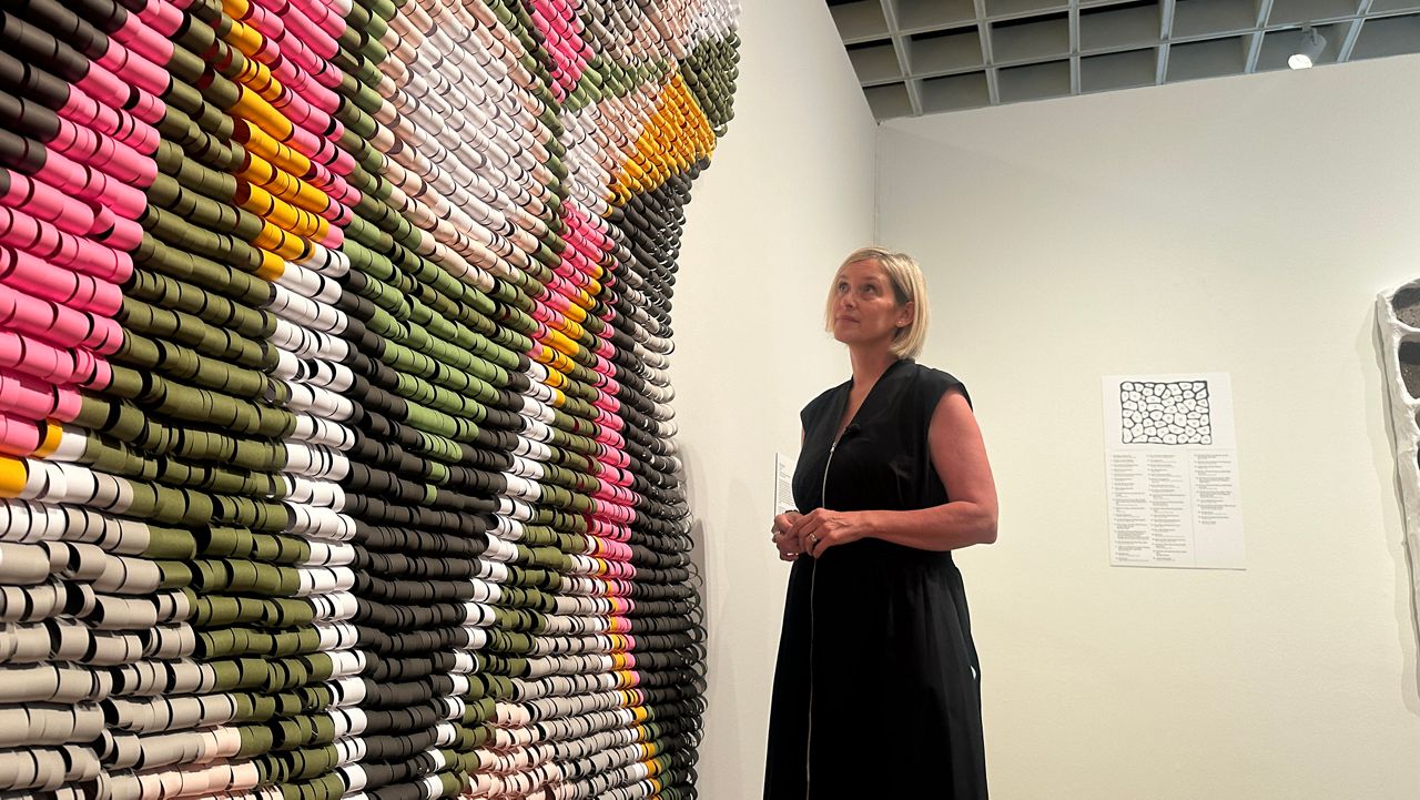 Central Florida artist Kelly Joy Ladd strolls in her exhibition at the Orlando Museum of Art. Ladd is one of ten Florida Prize artists, whose work is currently being highlighted. (Spectrum News)